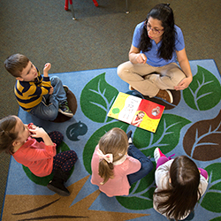 teacher engaged with children during activity on the carpet