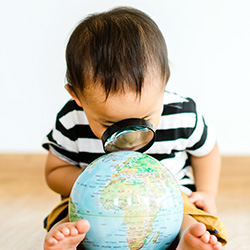toddler boy looking at globe with magnifying glass
