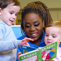 teacher reading to two toddlers