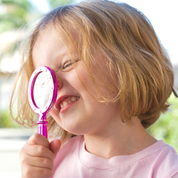 young girl looking through magnifying glass